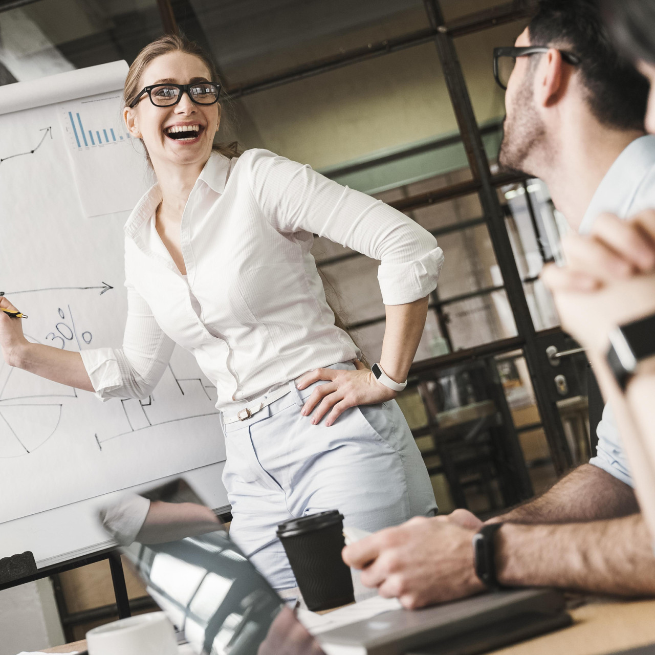 Photo of a happy woman at an office meeting with co-workers presenting a sales chart.