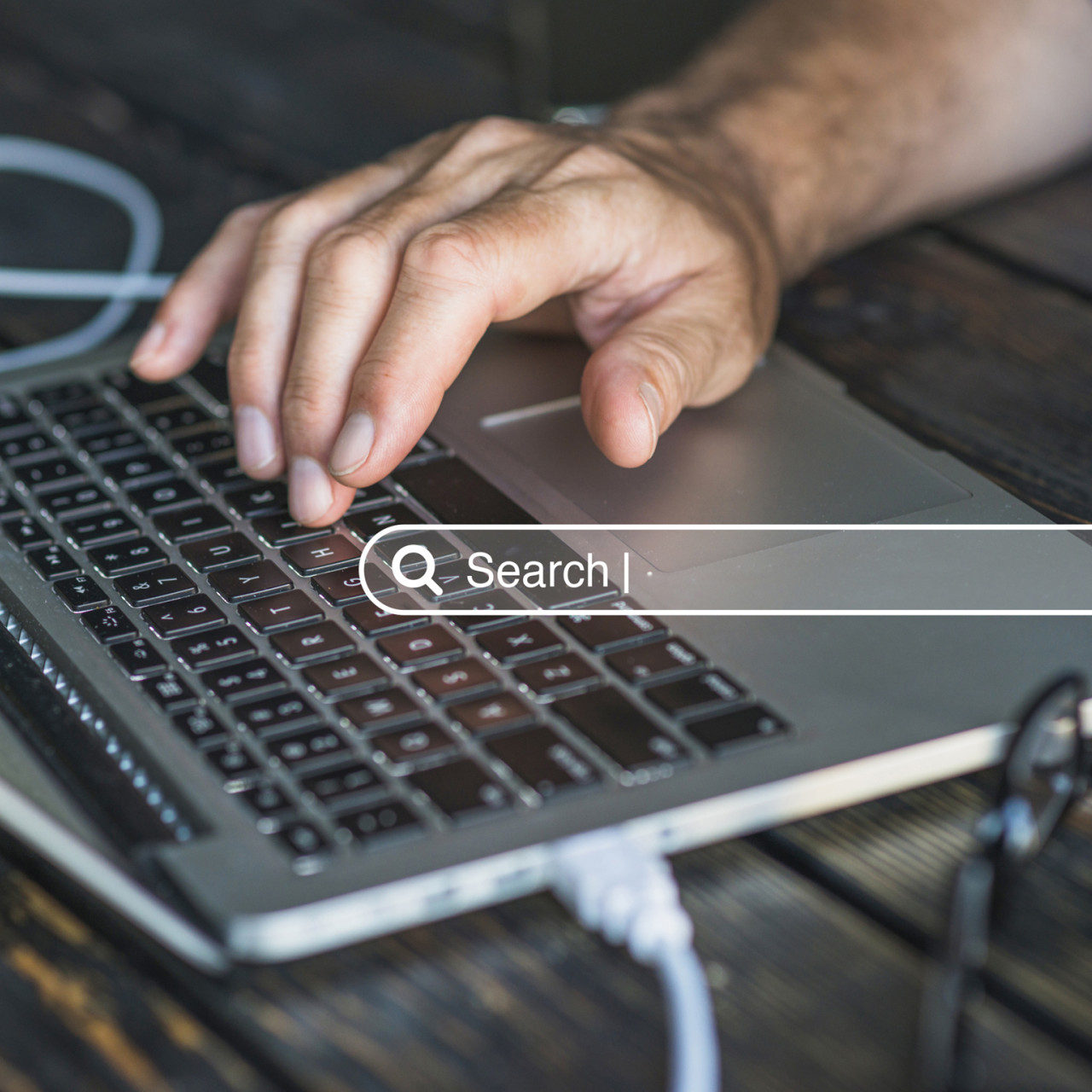 Photo of a man typing on his laptop with a search bar.