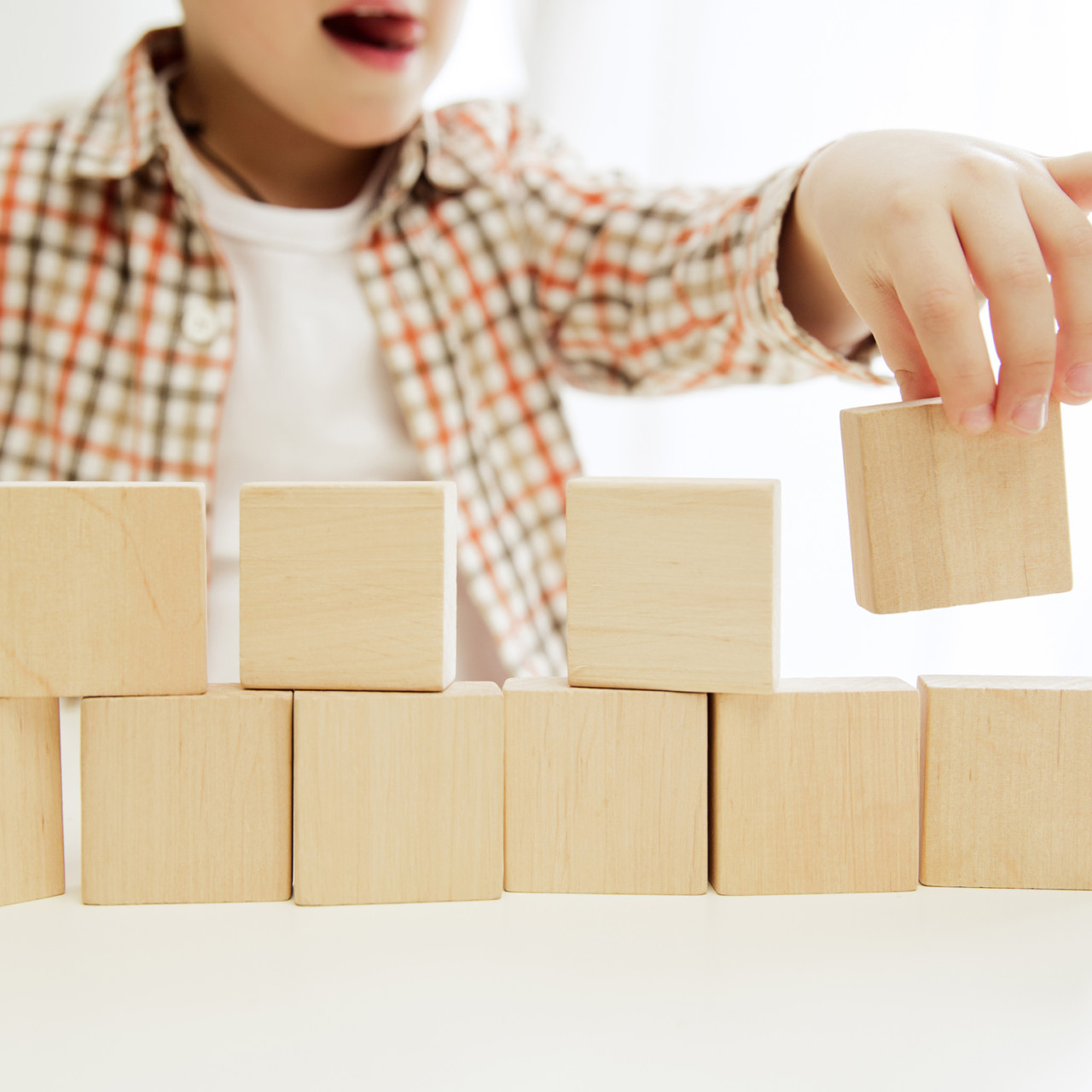 Photo of a child stacking wooden cubes.