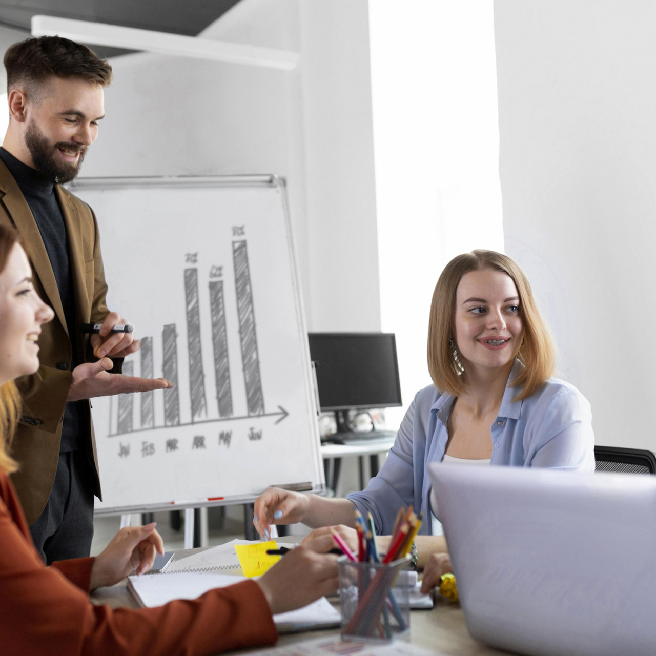 Photo of smiling co-workers in a meeting presenting sales growth numbers.