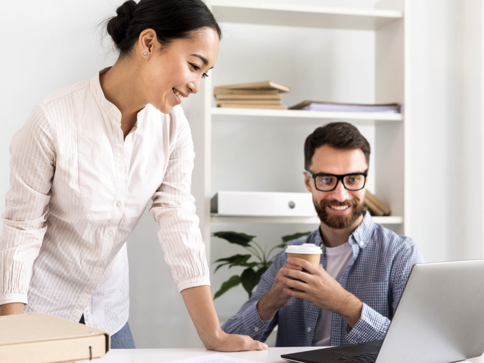 Photo of happy smiling co-workers looking at laptop screen.