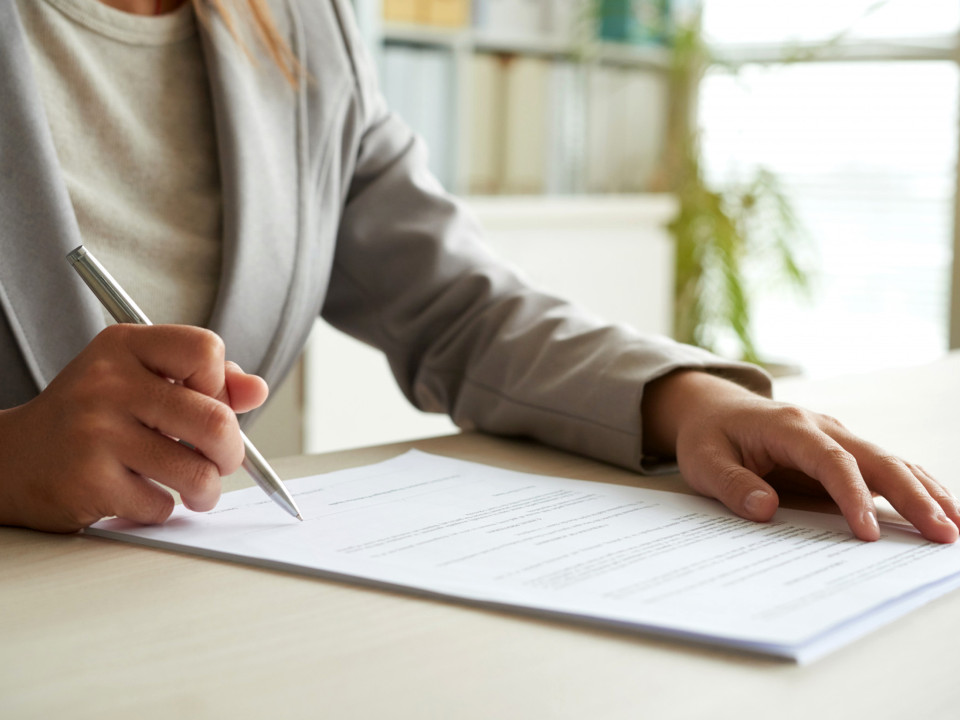 Photo of a businesswoman signing document.