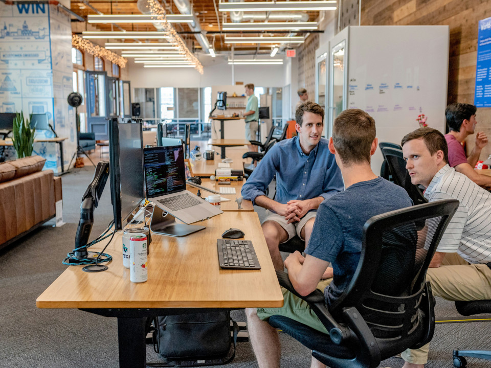 Photo of developers discussing among themselves at work desks.