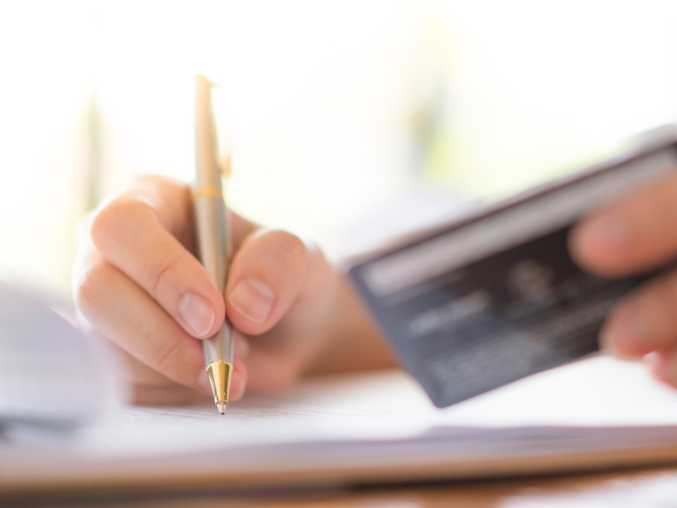 Photo of a person holding a credit card and pen.