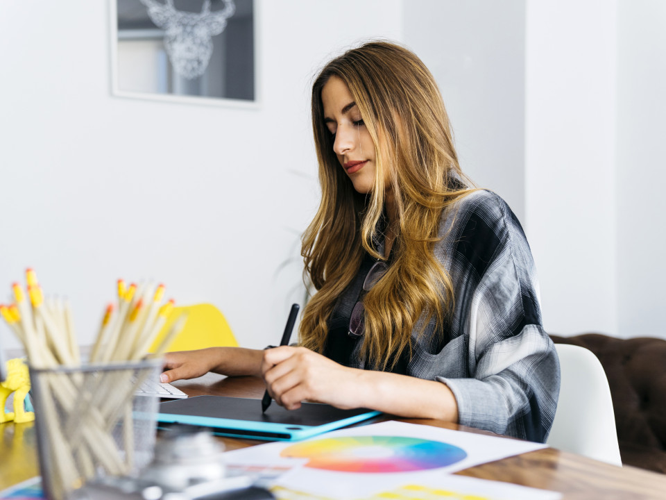 Photo of a female graphic designer working on her computer using a stylus.
