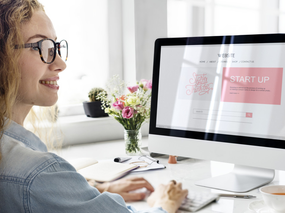 Photo of a smiling woman creating a website for her startup business.