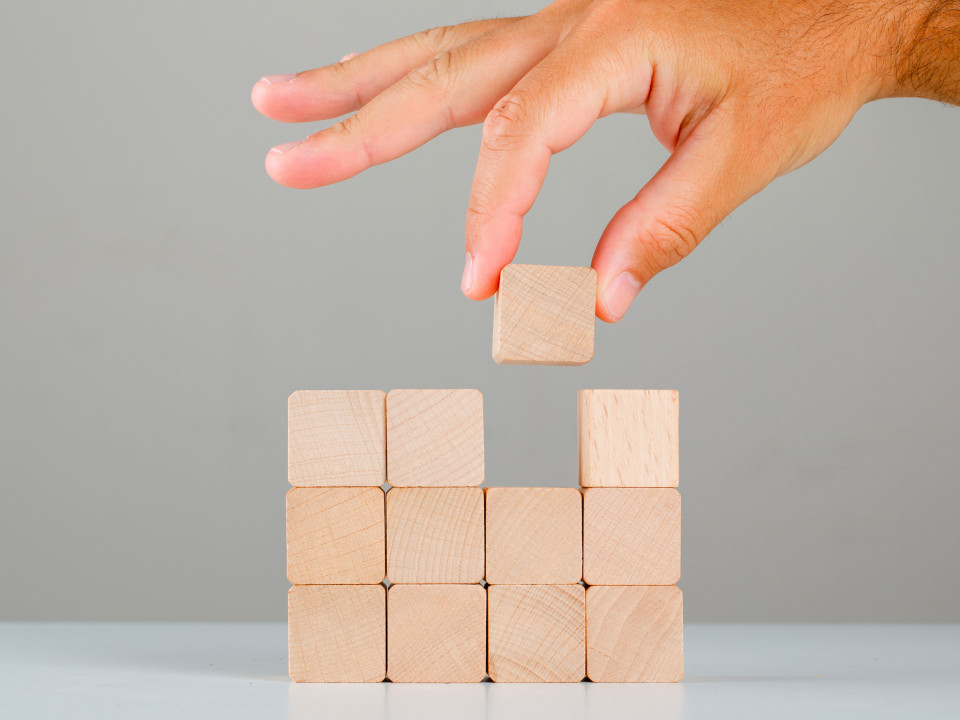 Photo of a hand stacking wooden cubes.
